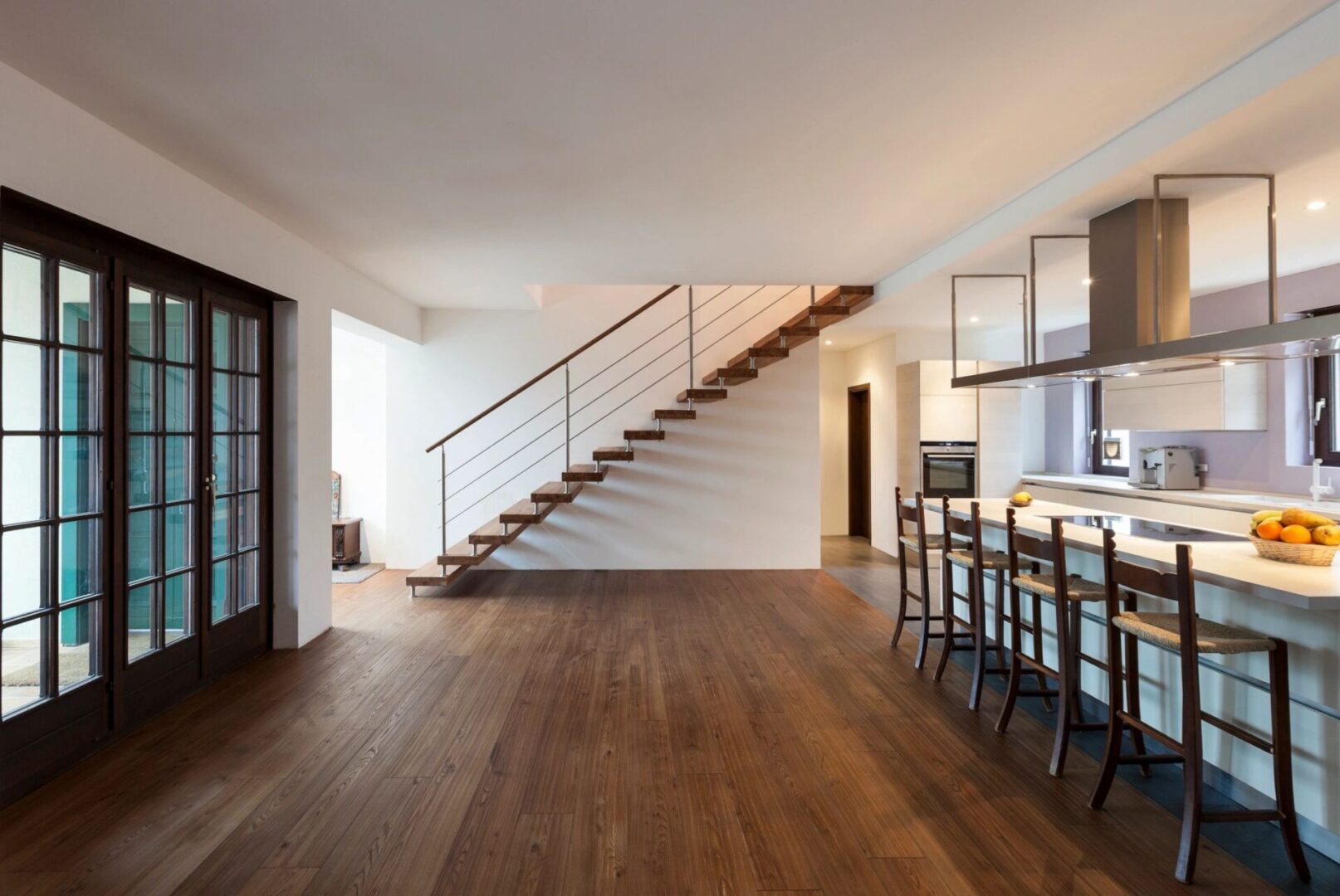 A room with wooden floors and stairs leading to the second floor.